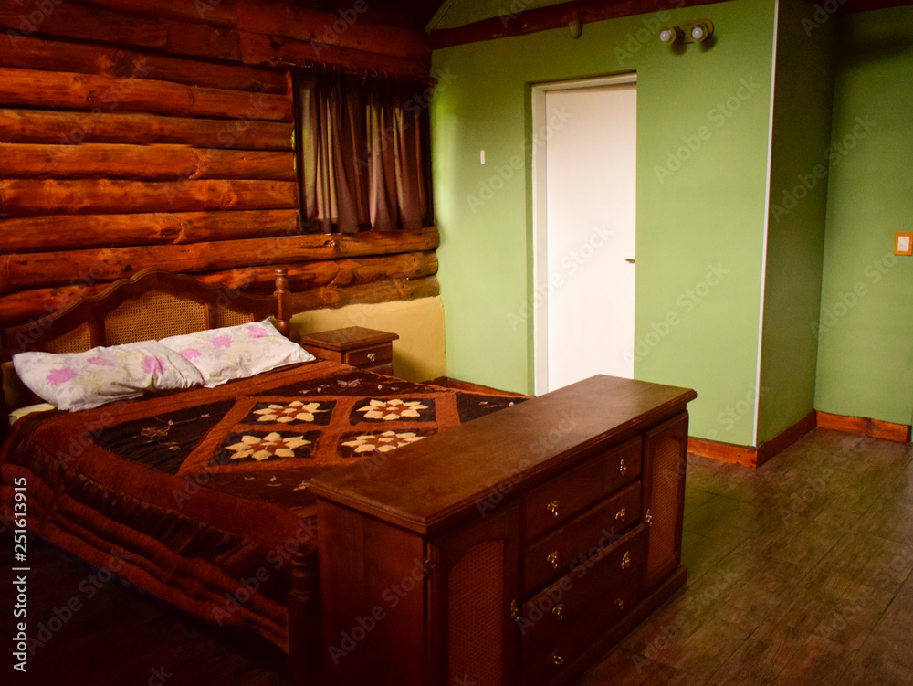 dormitorio de paredes verdes y la otra pared de troncos con cama matrimonial  y mueble antiguo Stock Photo | Adobe Stock