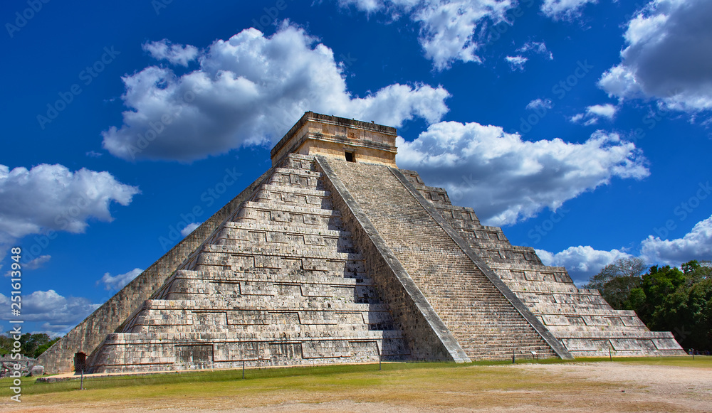 Sunny day with blue sky and white clouds. No people around. El Castillo (The Kukulkan Temple) of Chichen Itza, mayan pyramid in Yucatan, Mexico - Mar 2, 2018