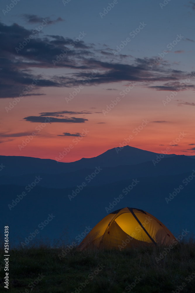 A yellow tent in mountains