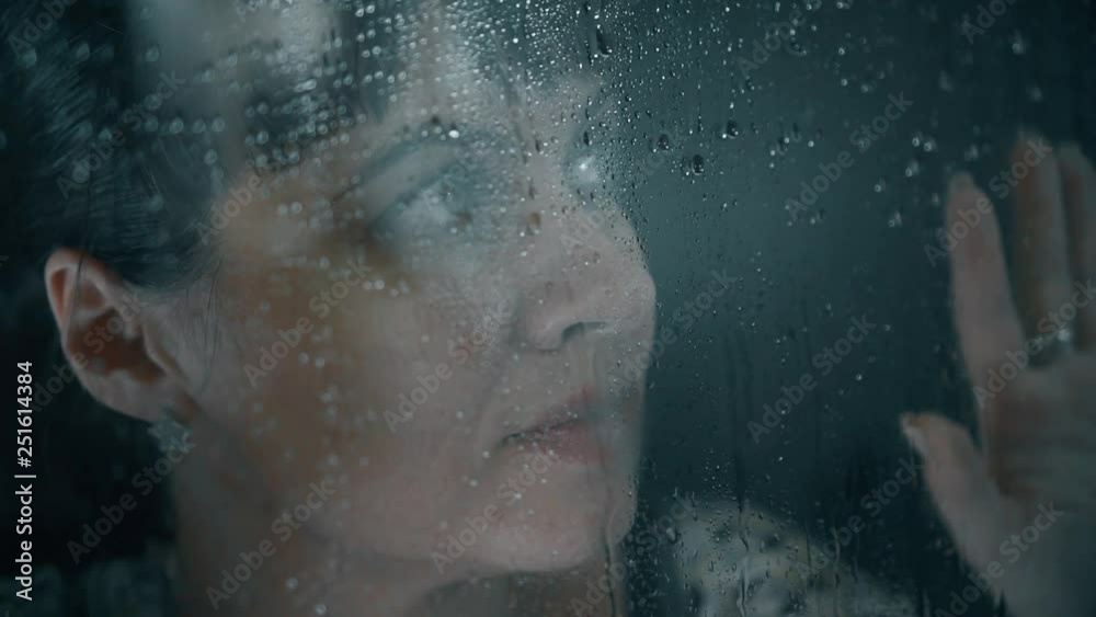 portrait of a girl behind the glass with water drops