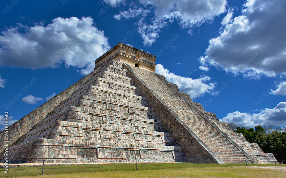 Sunny day with blue sky and white clouds. No people around. El Castillo (The Kukulkan Temple) of Chichen Itza, mayan pyramid in Yucatan, Mexico - Mar 2, 2018