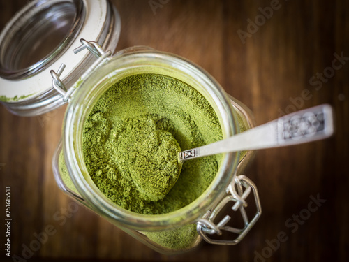 Moringa powder in a glass jar on wooden surface