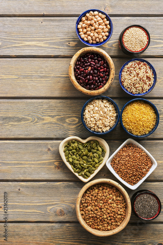 A set of various superfoods , whole grains,beans, seeds, legumes in bowls on a wooden plank table. Top view, copy space.