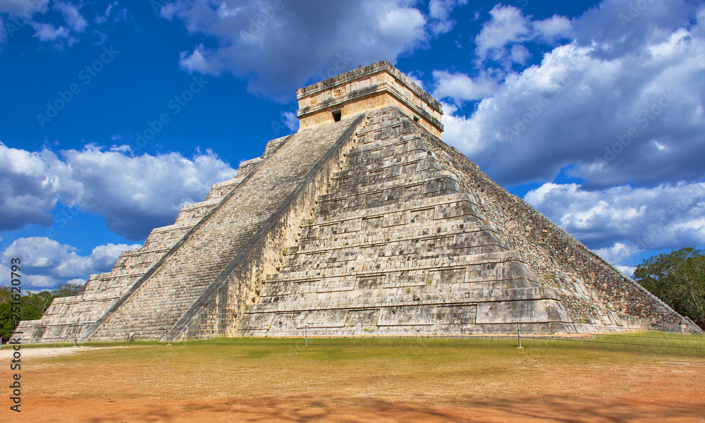 Sunny day with blue sky and white clouds. No people around. El Castillo (The Kukulkan Temple) of Chichen Itza, mayan pyramid in Yucatan, Mexico Sunny day with blue sky and white clouds. No people around. El Castillo (The Kukulkan Temple) of Chichen Itza, mayan pyramid in Yucatan, Mexico