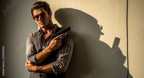 Young Caucasian male holding a gun in a sunset hotel