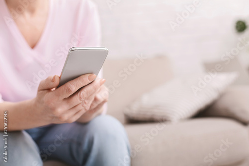 Cheerful senior woman using her smartphone at home