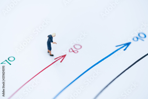 Miniature people: Small old women figures standing on age mile arrow. An aging society and pension concepts.