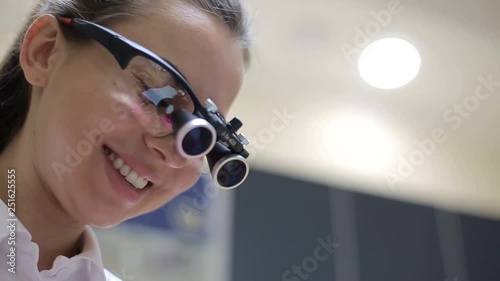 microsurgeon man in a white mask in special medical clothes and glasses with binocular loupes in the operating room. surgeon makes an operation. Hospital equipment photo