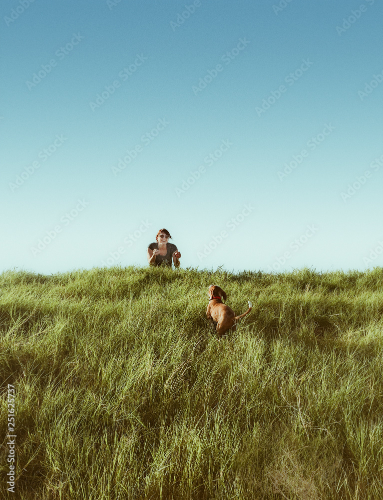 Smiling woman playing with dog in grassy field Smiling woman playing with dog in grassy field
