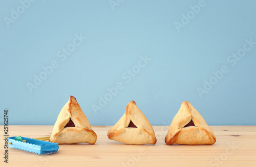 Purim celebration concept (jewish carnival holiday). Traditional hamantaschen cookies over wooden table and blue background.