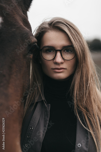 Portrait of woman wearing eyeglasses standing with horse in field