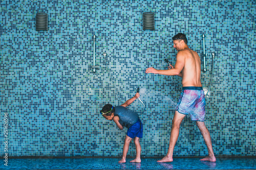 Father and son playing with water in an open shower