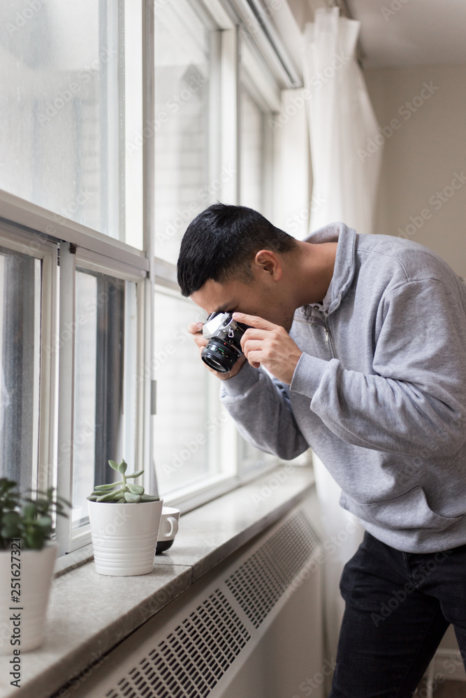 Man taking picture of houseplant with camera Man taking picture of houseplant with camera