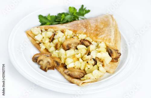 Thin delicious pancake with potatoes and mushrooms on white