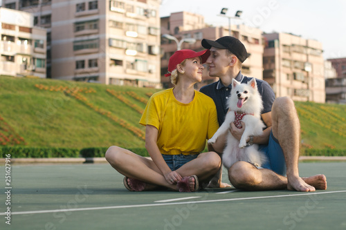 Couple with dog looking at each other while sitting on road