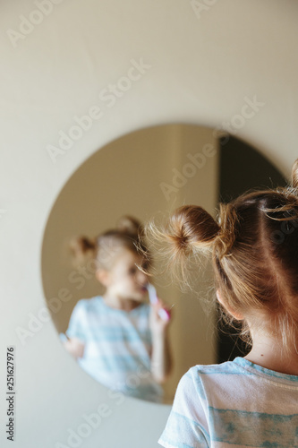 Girl brushing her teeth while looking in mirror