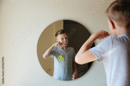 Boy brushing his teeth while looking in mirror