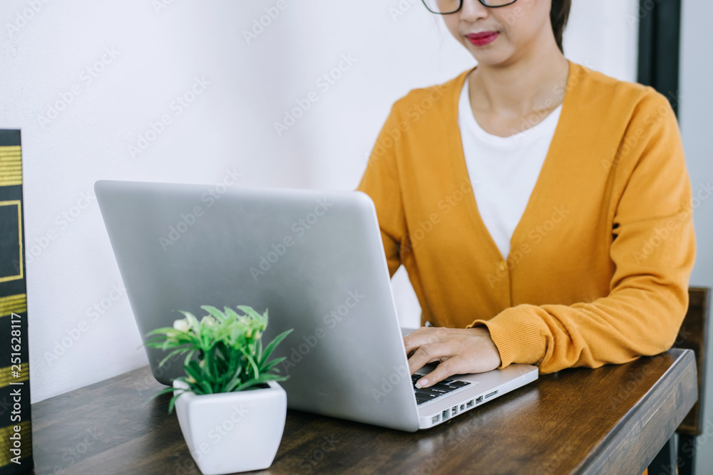 Happy casual young asian woman working in home or small office with using a laptop and document report on desk as a freelancer Happy casual young asian woman working in home or small office with using a laptop and document report on desk as a freelancer