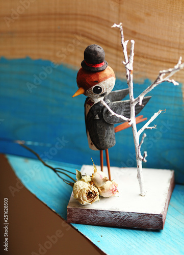 Fun wooden bird sparrow in the hat and dinner jacket with dried rose. photo