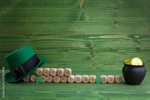 Happy St Patricks Day wooden blocks with leprechaun hat on a wooden background photo