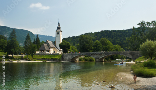 Picturesque view of the Church of St. John the Baptist, bridge, Julian Alps mountains and lake, Bohinj, Slovenia