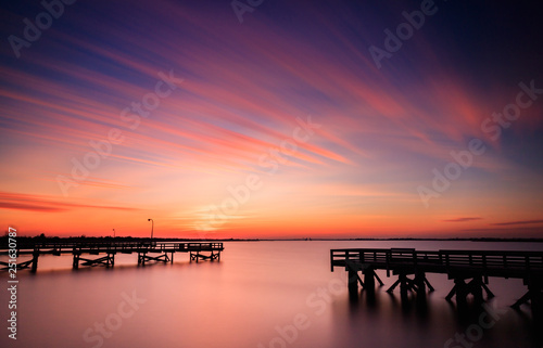 Vibrant orange and pink pastel color sunset over fishing piers. Perfectly still water