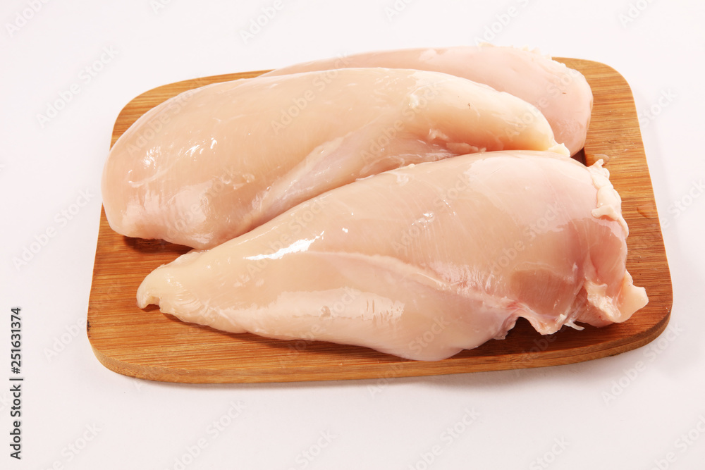 Raw chicken breasts and spices on wooden cutting board, close up Raw chicken breasts and spices on wooden cutting board, close up
