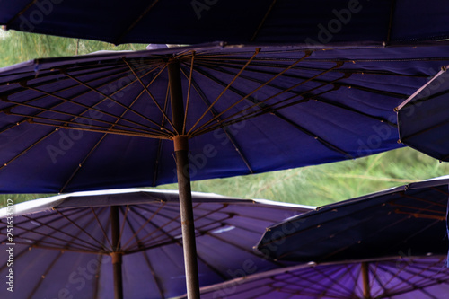 Close up under a lot of old purple beach umbrellas