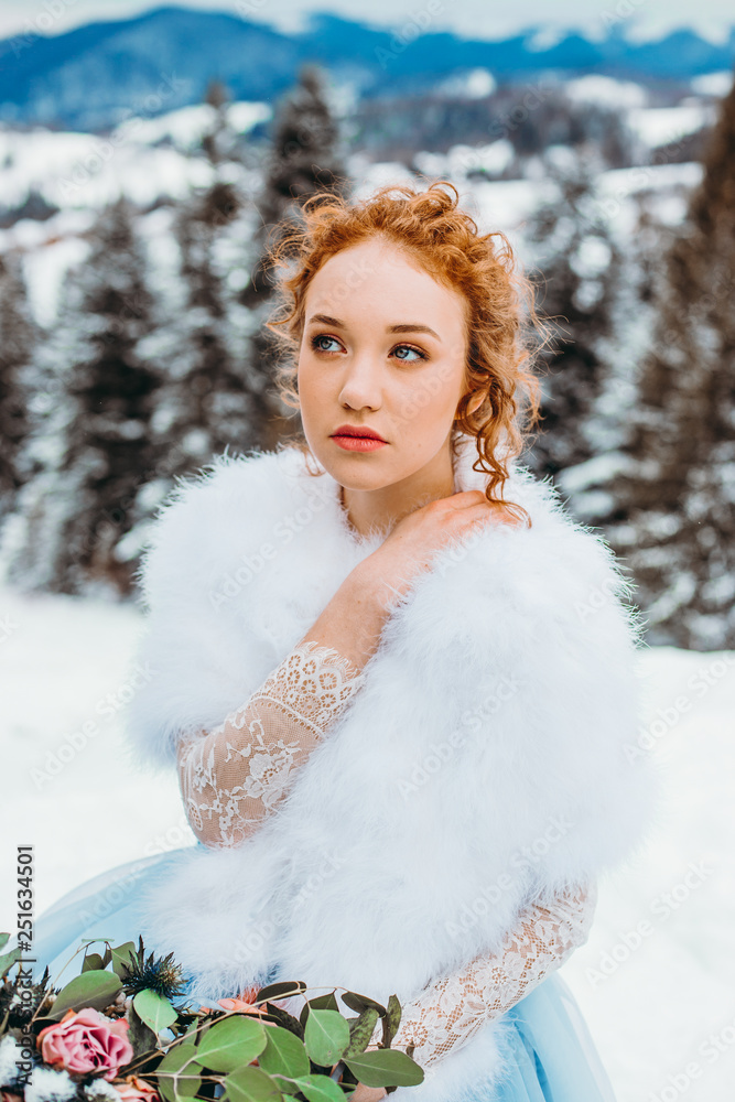 Elegant red-haired girl with a bouquet in her hands sitting on a chair against the backdrop of winter mountains Elegant red-haired girl with a bouquet in her hands sitting on a chair against the backdrop of winter mountains