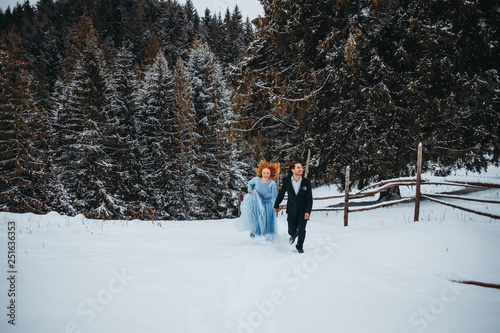 Pretty couple walking in the snowy forest in the mountains