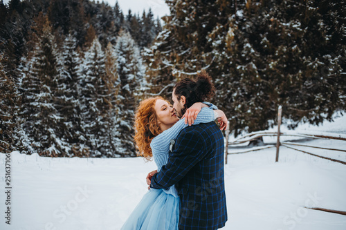 Crazy couple kissing each other in a snowy forest in the mountains © Yuliia