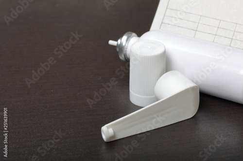Inhaler for the treatment of respiratory organs. Spray can and cap white. Next recipe to buy. On a dark surface.