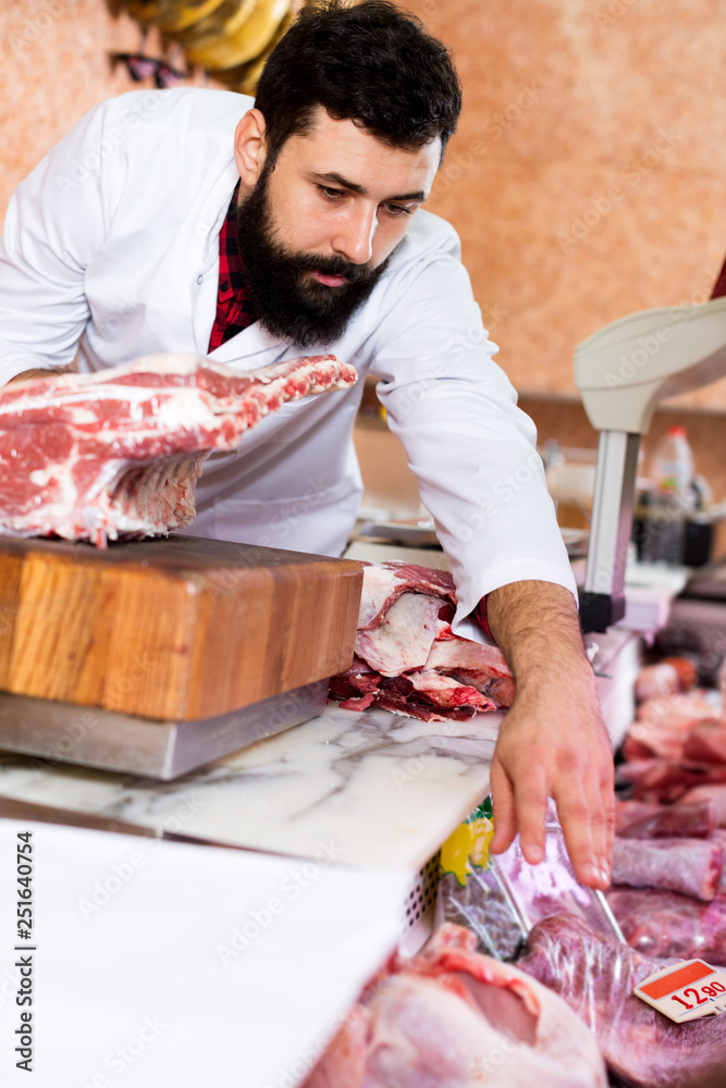 Male shop assistant carving meat
