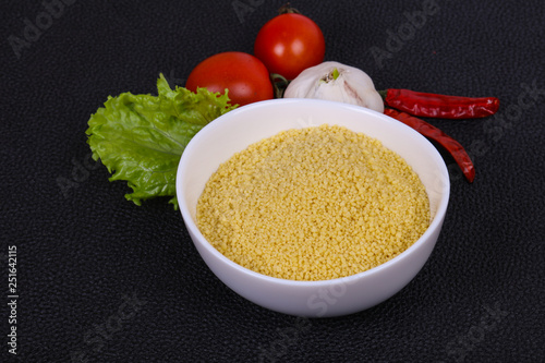 Raw couscous in the bowl served salad leaves, tomato and pepper photo