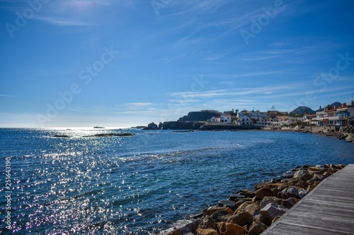 Blue skies and bluer water frame houses on the rocky beachfront of Cabo de Palos, Spain