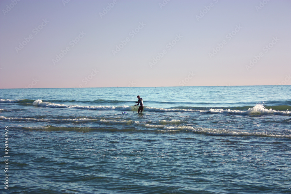 Fototapeta premium man plunged in the sea fishing and collects tellines or clams or other seafood on a winter day
