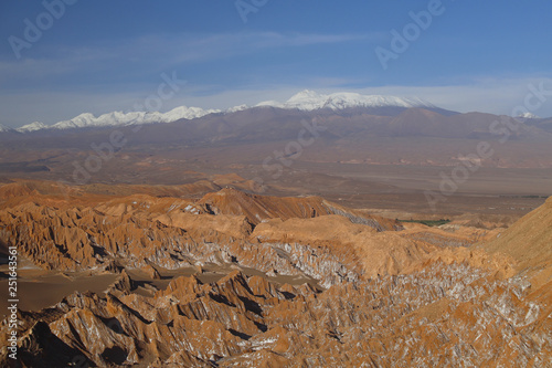 Valle de la Luna (Valley of the Moon) and snow-covered volcanoes in the background, the white in the foreground is salt, Atacama Desert, Chile