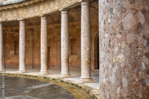 A close-up of a palace pillar showing its texture with identical pillars in the background surrounding a circular plaza in Granada, Spain 