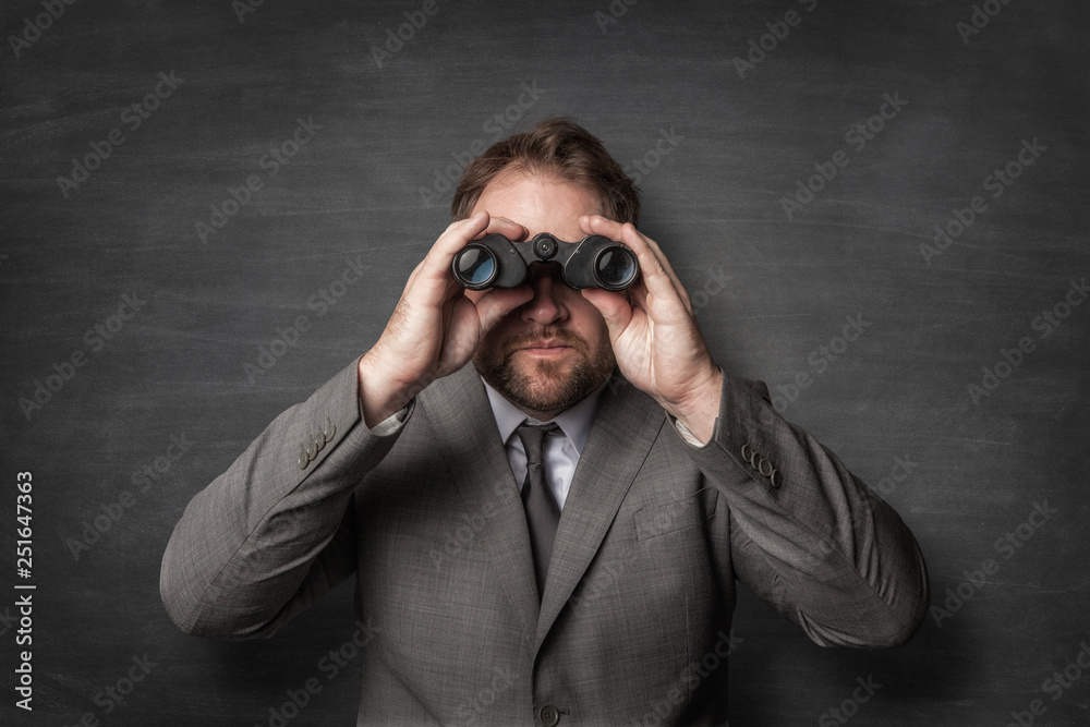 Businessman in a suit watching with binoculars Businessman in a suit watching with binoculars
