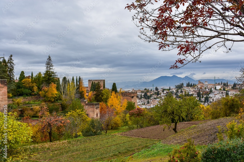 The ancient palace of Granada, Spain stands guard over the city, surrounded by the autumn coloured leaves of tall trees.
