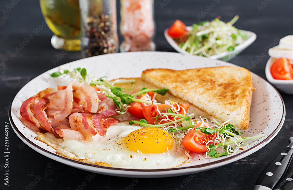 English breakfast - toast, egg, bacon and tomatoes and microgreens salad. English breakfast - toast, egg, bacon and tomatoes and microgreens salad.