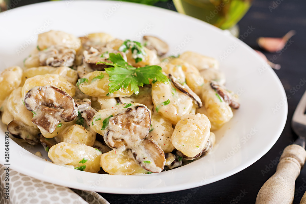 Gnocchi with a mushroom cream sauce and parsley in bowl on a dark background Gnocchi with a mushroom cream sauce and parsley in bowl on a dark background