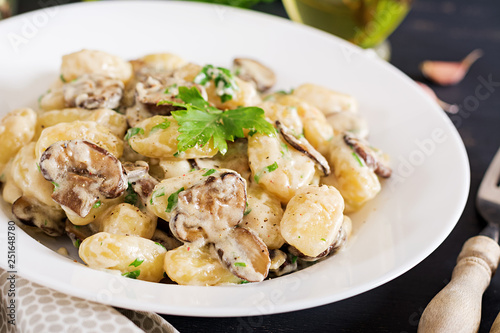 Gnocchi with a mushroom cream sauce and parsley  in bowl on a dark background