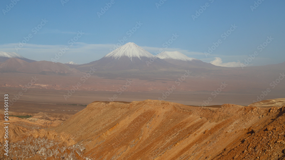 View of the landscape of rocks of the Mars Valley (Valle de Marte) and snow-covered volcanoes, Atacama Desert, Chile