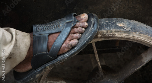 Fotografía macro del pie de un trabajador en la India, haciendo girar una rueda de madera