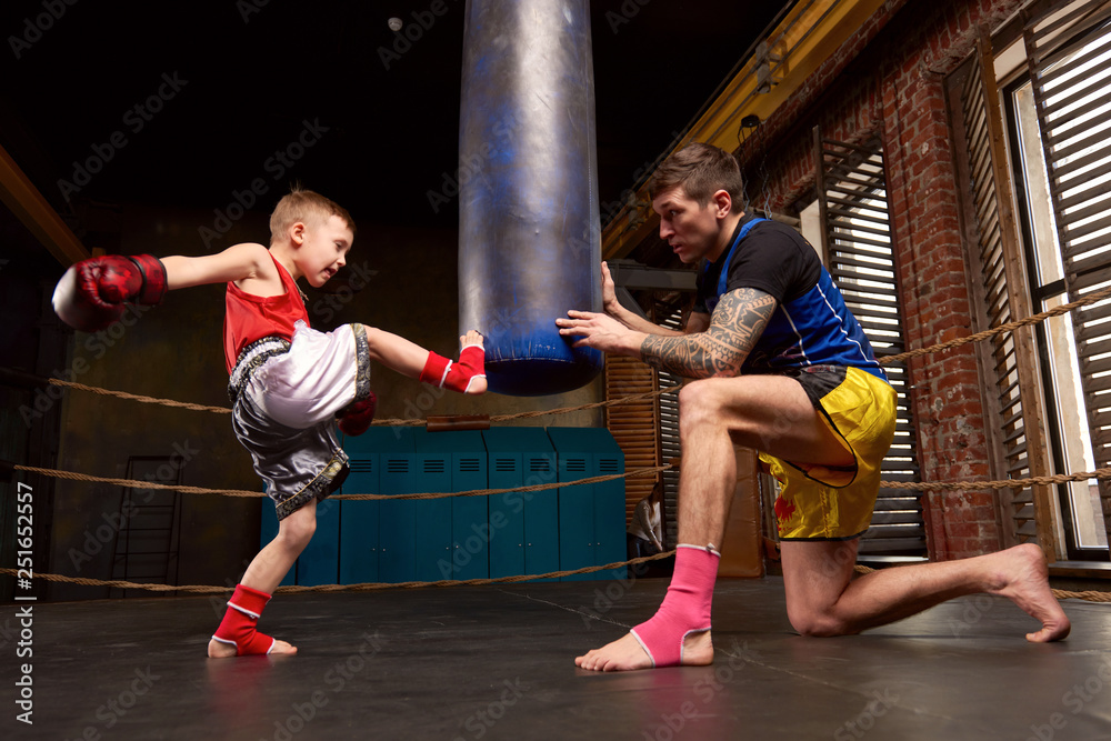 Trainer teaching a kid how to hit punches. Kid wearing boxing gloves and  head guard training with his coach inside a boxing ring Stock Photo | Adobe  Stock
