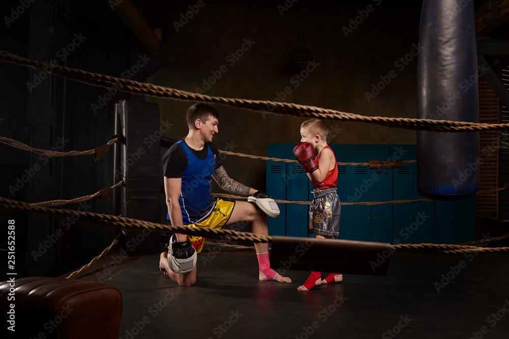 Trainer teaching a kid how to hit punches. Kid wearing boxing gloves