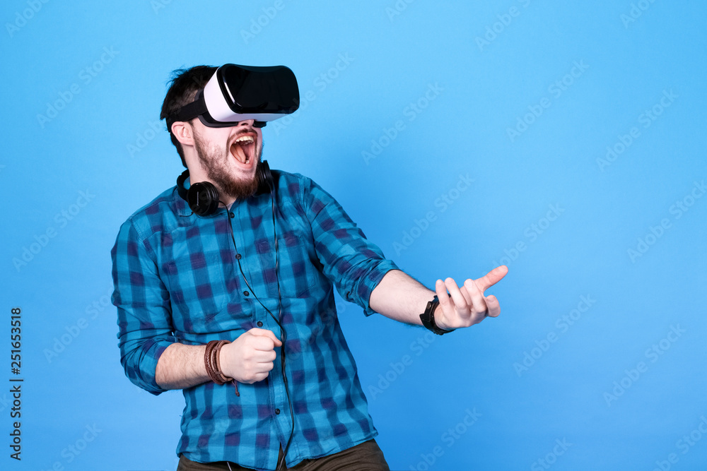 bearded man in glasses of virtual reality, emotionally playing shooters in VR on blue background bearded man in glasses of virtual reality, emotionally playing shooters in VR on blue background