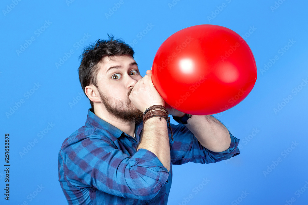 Man inflating a red balloon by mouth, image on a blue background Man inflating a red balloon by mouth, image on a blue background