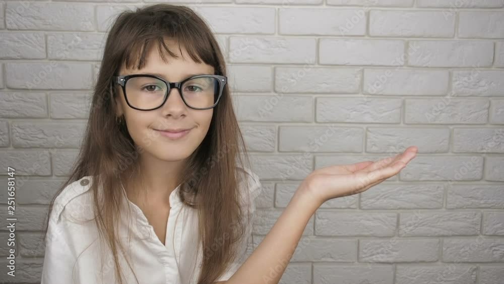 A child with glasses offers goods. A cute girl shows an empty palm. A child with glasses offers goods. A cute girl shows an empty palm.